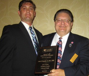 Jeffrey Fisher, Executive Director of the Brevard County Medical Society, presents Dr. John Potomski, Jr., with an award for 30 years of medical service to Brevard. (Space Coast Medicine & Active Living image)