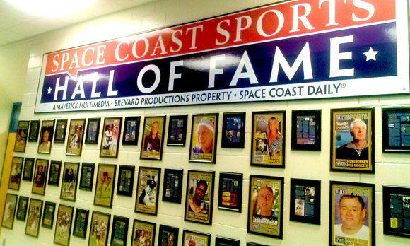 The main athletic building on the Melbourne Campus will host the 83-member Hall of Fame, as portraits of the Hall of Famers are displayed on the wall in the building’s main hallway that runs parallel to the gym and outside the athletic department offices. Memorabilia items and related sports artifacts will be added to the display over time. (Space Coast Sports Hall of Fame image)