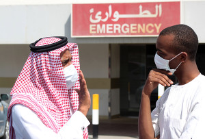 Men wearing surgical masks as a precautionary measure against the novel coronavirus, speak at a hospital in Khobar city in Dammam