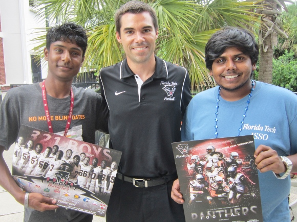 Florida Tech Asst. Athletic Director Ryan Jones, center, talks Panther football with Shadhab Tamboli, left, and Mr. Uday, right, as they check out 2014 Panther Football team posters distributed at the recent welcome event for international students. (Cyndi Byars image)