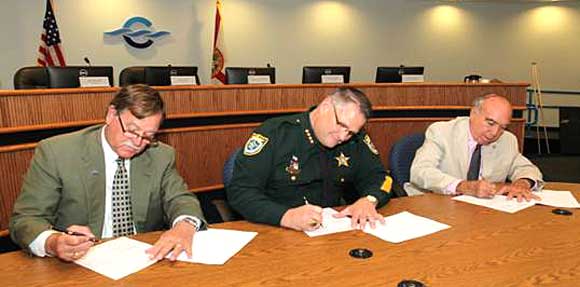 Canaveral Port Authority Chairman Tom Weinberg, left, Brevard County Sheriff Wayne Ivey, center, and Port Commission Secretary/Treasurer Frank Sullivan sign the law enforcement agreement. (Port Canaveral image) 