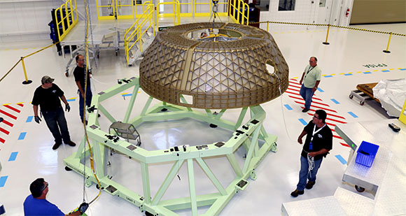 Inside the Commercial Crew and Cargo Processing Facility, engineers move the upper dome assembly of the CST-100 Starliner structural test article onto a work stand. What was Bay 3 of the space shuttle era's Orbiter Processing Facility now is being modernized by Boeing to prepare its Starliner spacecraft currently under development for the Commercial Crew Program. (NASA.gov image) 