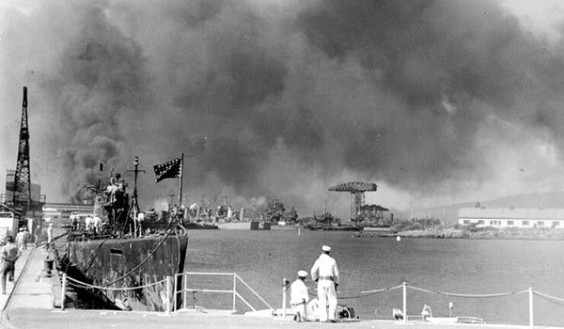 The view of the Pearl Harbor Navy Yard from the Submarine Base during the Dec. 7, 1941, attack. The USS Narwhal is in the left foreground. In the distance are several cruisers, with large cranes and 1010 Dock in the right center.