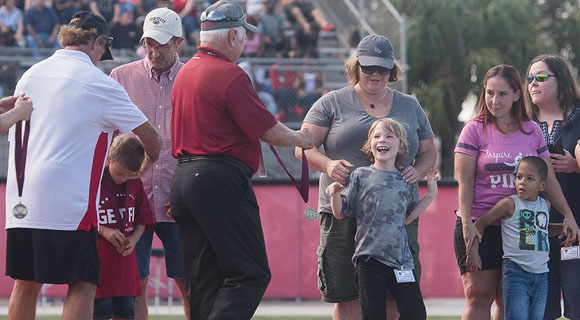Doug Flutie (left) and FIT President and CEO Dr. Anthony Catanese (right) present medals to children at halftime of the Nov. 7 football game. (Florida Tech image)