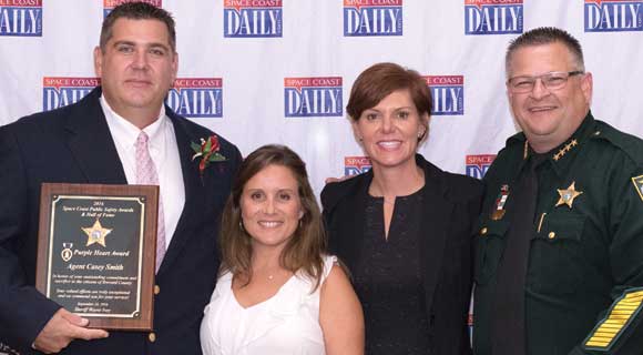 Brevard County Sheriff's Agent Casey Smith, left, is presented with the "Award of the Purple Heart" by Sheriff Wayne Ivey and his wife Susan during the first annual Space Coast Public Service Awards & Hall of Fame Induction Gala at the King Center on September 24. The Space Coast Daily Awards Committee reviewed an incredible list of nominations and recognized more than 100 extraordinary Space Coast Public Servants during this very special event. (Steve Wilson image)