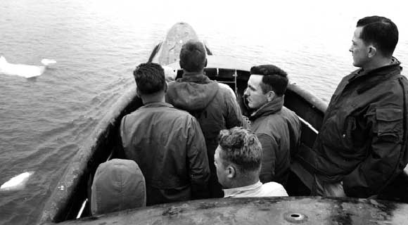 Commander William R. Anderson, USN, Commanding Officer of USS Nautilus (SSN-571), far right, on the bridge during a period of low visibility as the submarine prepares to pass under the North Pole, August 1958. National Archives photograph, USN 1037145